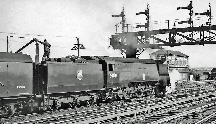 Down ‘Man of Kent’ at Ashford station
20th April 1957
The Down 'Man of Kent', 12.55pm Charing Cross to Margate via Dover, is headed by Bulleid Light Pacific no.34084 '253 Squadron' (built November 1948, withdrawn (air-smoothed) October 1965). 
“Note the fireman perched precariously on the tender 
while they are taking water - no water-troughs on the SR”.
© Ben Brooksbank (CC-by-SA/2.0)

