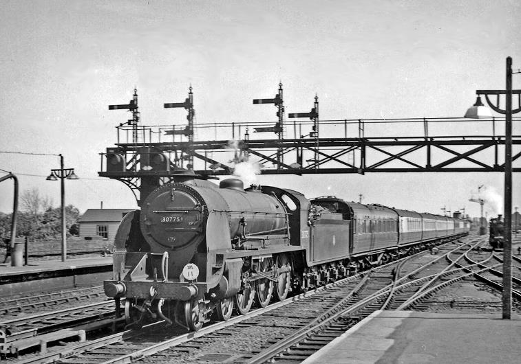 Up Special empty stock entering Ashford with a 'King Arthur'
20th April 1957
Maunsell Class N15 no.30775 'Sir Agravaine' (built June 1925, withdrawn February 1960) steams through under a fine gantry of signals, passing an H class tank engine.
 Ben Brooksbank (CC-by-SA/2.0)
