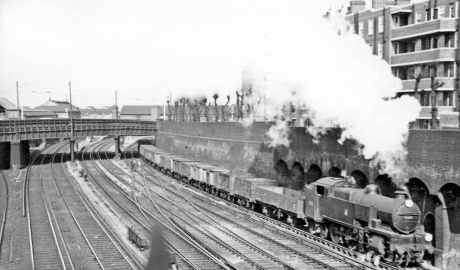 Down Central Section goods, west of Clapham Junction
18th March 1957
Still passing under St. John s Hill overbridge at Falcon Junction on the Down Central Section Slow line towards Balham is a goods headed by Maunsell W class no.31921 (built October 1935, withdrawn June 1963), one of the class of fifteen all of which spent almost the whole of their lives on cross-London freight work from SR Yards.
Ben Brooksbank (CC-by-SA/2.0)