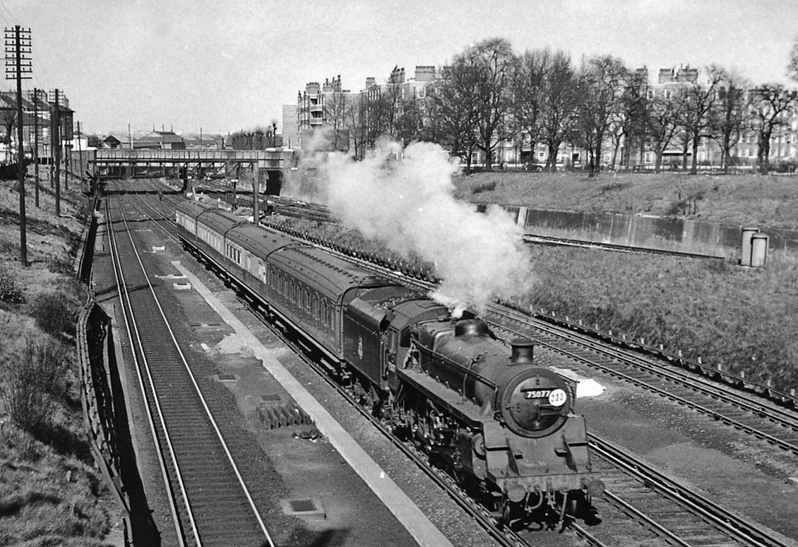 Waterloo - Basingstoke train west of Clapham Junction
22nd March 1957
Just about to pass under Battersea Rise overbridge, the 1.54pm Waterloo - Basingstoke semi-fast is headed by BR Standard 4MT no.75077 (built December 1955, withdrawn July 1967). After the loose SK coach is a CLC-liveried Maunsell 3-set with four-compartment BSK coaches. Climbing up on the right is the ex-LB&SC main line from Victoria to East Croydon, Brighton etc.
© Ben Brooksbank (CC-by-SA/2.0)

