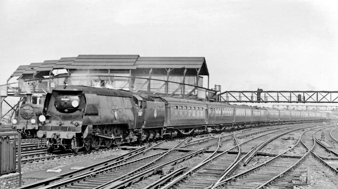 Waterloo - Weymouth express at Clapham Junction
2nd April 1958
Looking north from platforms 11/12 Down express headed by Bulleid Light Pacific no.34107 'Blandford Forum' (plain 'Blandford' until October 1952), built April 1950, withdrawn (air-smoothed) September 1964. Behind it is an M7 0-4-4T and 'A' Box, with its massive wartime steel canopy - later to collapse.
© Ben Brooksbank (CC-by-SA/2.0)
