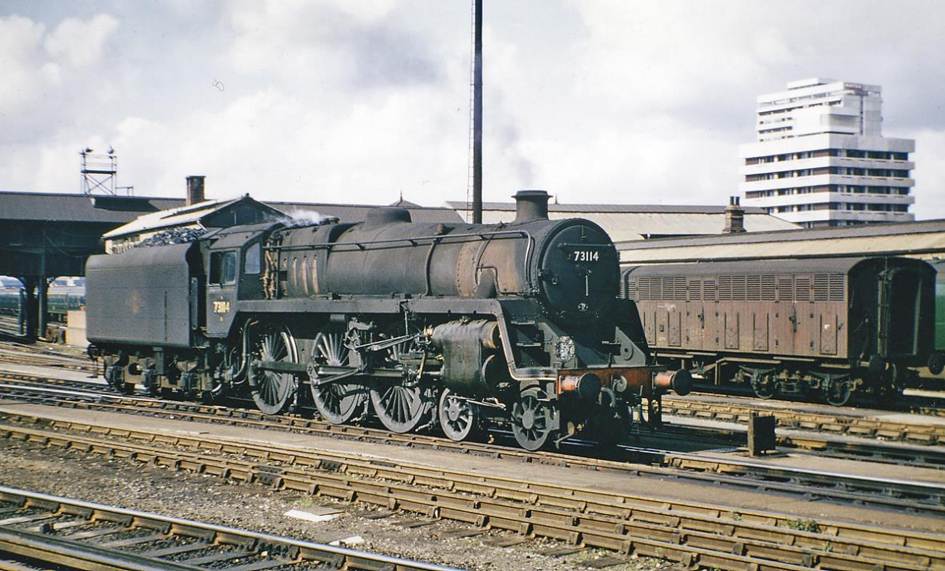 Clapham Junction (Windsor Lines), with BR Standard 4-6-0
9th September 1965
From Up Main platforms 7/8 across the lines into the Carriage Yard to the Windsor Line platforms 1-6. The filthy BR Standard 5MT is no.73114 'Etarre' (built November 1955, withdrawn June 1966), latterly carrying the name previously borne by 'King Arthur' class no.30751 which was withdrawn in June 1957.
In Alfred Tennyson's Idylls of the King, Sir Pelleas (knighted by King Arthur) deeply loves the maiden named Etarre (who does not return his affection).
Ben Brooksbank (CC-by-SA/2.0)