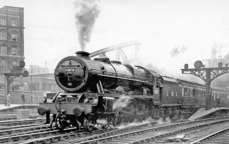 BloodandCustard
Paddington Station
1948 Locomotive Exchanges
LMS 'Royal Scot' leaves Paddington for Plymouth 
25th May 1948
From the extension of Platform 1, rebuilt LMS 'Royal Scot' 7P no.46162 'Queen's Westminster Rifleman' is leaving Platform 3 at Paddington, on a trial run with a dynamometer-car, with the 1.30pm express to Plymouth. 
After the Natonalisation of the Big Four Companies on 1st January 1948, in the Summer a succession of trials of express, mixed-traffic and heavy-freight locomotives was made, to determine which - if any - of the Companies' modern locomotives was the 'best', before new Standard designs were drawn up for the whole of British Railways. 
Each Railway tried out all the others' selected types, except that owing to loading-gauge restrictions the Great Western types could not be tested on the former LMSR or SR main routes. Living in London - and with elastic Graduate Student hours - I was able to rush round the termini and get some photographs: here I captured one of the Express Locomotive trials, of an ex-LMS locomotive on the ex-GWR.
 Ben Brooksbank (CC-by-SA/2.0)
