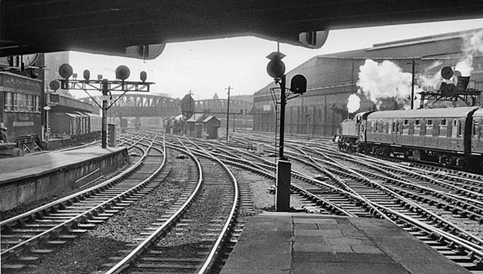 BloodandCustard
Paddington Station
Paddington s approach
28th June 1962
 Searchlight  signals in abundance
 I was at the end of Platforms 4/5, underneath Bishop's Bridge Road. Beyond the end of No. 1 on the left is Paddington Departure Signalbox, then the parcels station. In the centre distance two 0-6-0 Pannier tanks wait between empty stock jobs; Westbourne Bridge is beyond and in the dim distance Royal Oak (LT) Station can just be glimpsed. On the right, a 61XX 2-6-2T leaves with the empty stock of an Up express and passes Paddington Goods Station. 
  Ben Brooksbank (CC-by-SA/2.0)