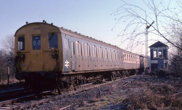 Illuminated by some bright morning sunshine, 3R unit no.1202 starts away from Edenbridge on Saturday 3rd February 1979 working a Tonbridge to Reading train with the 'eight wheel driving cab' leading! At this date the unit was misformed, running for a while with 6L trailer 60551 (borrowed from unit no.1031) and it has two four-bay passenger saloons whereas a genuine 6S car had a three-bay saloon adjacent to the toilet end. The signalman is visible inside the neat little SER style box, about to drop the starter back to danger behind the train, a nice short pull there! Unit nos.1202 own TSO 60504 was at Selhurst being repainted into blue /grey at this time.
 John Atkinson
