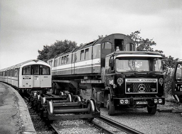 www.BloodandCustard.com Isle of Wight standard stock.

27th September 1989 and following the unloading of cars 123 & 223 (unit no.483003)  car 32 (ex.485043 withdrawn 4th September 1989) has been craned onto a low-loader at Sandown before going back to the mainland for scrapping by Vic Berry.
Note the black-painted cab-end of 32; originally 3 TIS unit no.034 it became an intermediate Trailer car during overhaul in June 1985 thence into unit no.485043.
© Chris Wilson

