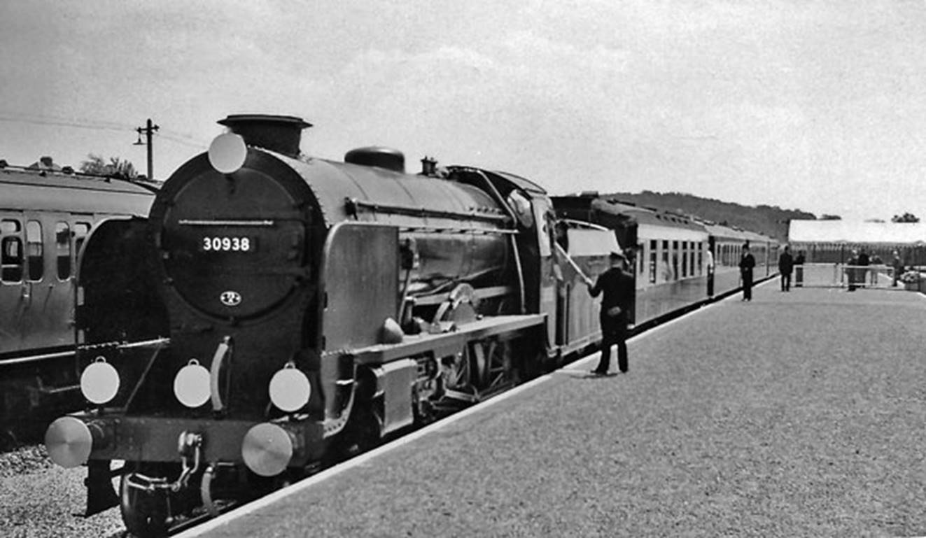 Tattenham Corner 3rd June 1959
View towards Purley on 3rd June 1959 and the Station is prepared for HM the Queen to attend the year’s primary horse-race. Her Pullman train is hauled by a resplendent 'Schools' locomotive no. 30938 'St Olaves’ (with Lemaitre double-chimney). Note headcode and Stationmaster guiding the driver to the exact stopping point.
© Ben Brooksbank (CC-by-SA/2.0)
