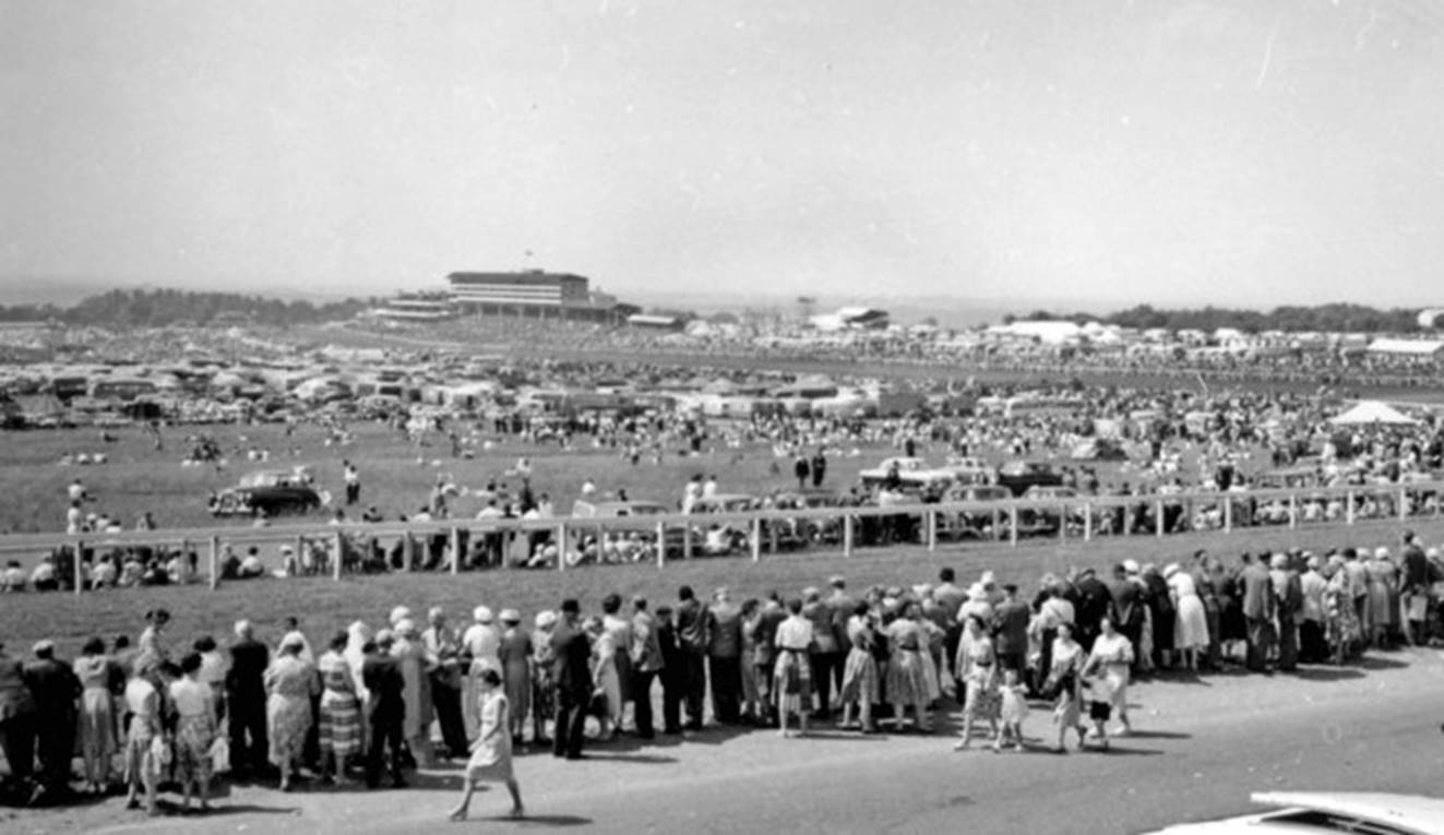 Derby Day 3rd June 1959
(seen from Tattenham Corner)
West from the famous Corner, with the Grandstand dominating the background. What a happy - and smart-looking - throng! The Derby was won by 'Parthia'.
 Ben Brooksbank (CC-by-SA/2.0)
