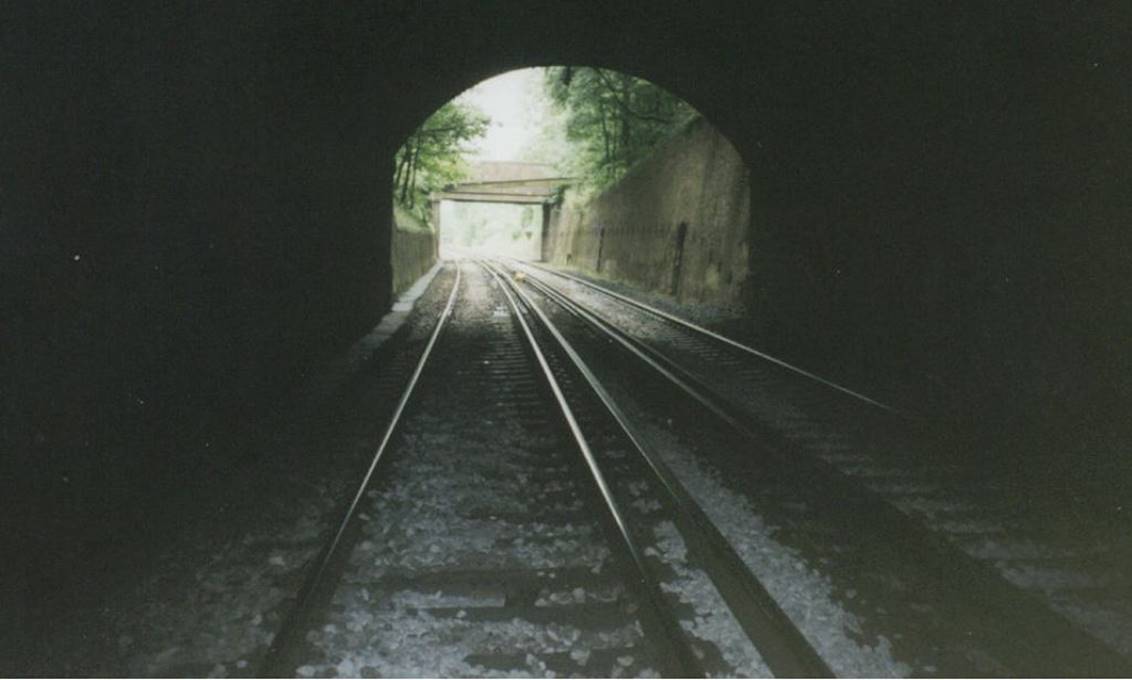 www.BloodandCustard.com

The brick sides of the former covered way from inside the north-end portal on the Up Quarry Line. Note the staff recesses, pipe bridge and public footbridge.
Tamping operations had been undertaken overnight (29th /30th July 2003)
 Colin Watts
