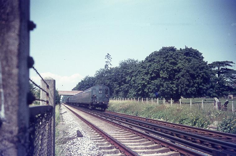 Taken from the foot crossing and with the old A249 bridge in the background, SR-type 2 HAP unit in original green livery on Bobbing Bank approaches Western Junction (on the outskirts of Sittingbourne) sporting 82 headcode (Charing Cross to Ramsgate via Chatham service).
The line of trees has long gone and the green meadow is now a housing estate.  
 BloodandCustard
