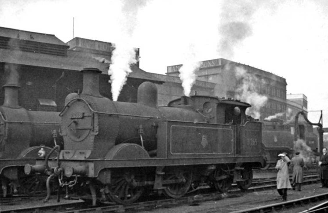 Transfer freight from Battersea Yard to Brent Sidings (Cricklewood) passing Stewarts Lane (alongside the big Harrods furniture repository) on 15th February 1958. The freight is hauled by an LMS-type Ivatt 4MT no.43121 (built August 1951, withdrawn November 1967); on the right is an unidentified ex-SECR C-class locomotive.
View is northward, from Stewarts Lane Locomotive Yard (the Depot is behind photographer) in the complex of SR lines near Queens Road (Battersea) station. The bridge carries the South London line (Victoria - London Bridge), Wandsworth Road being the next station off to the right.
© Ben Brooksbank (Geograph/CC-by-SA)
