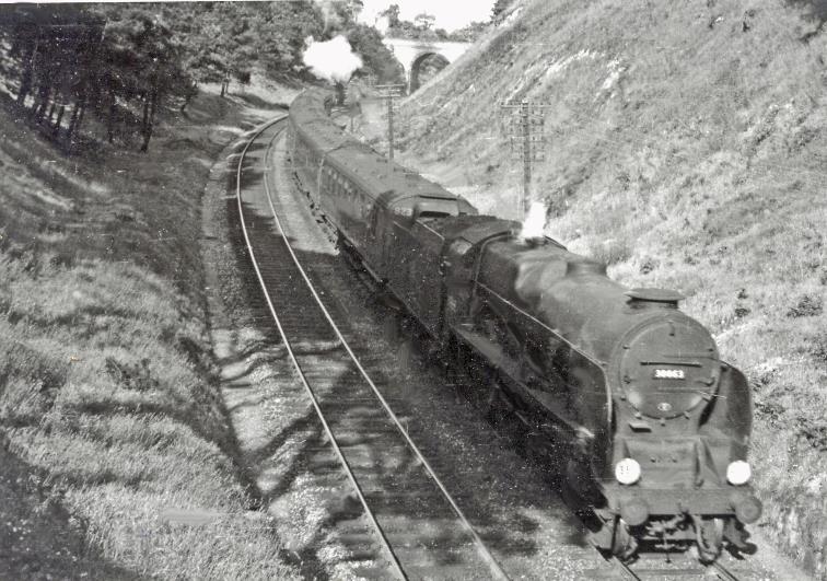 Up train from Weymouth identified as ascending Parkstone bank on 16th June 1951 (view westward towards Poole). This train has taken on a banker from Poole and is headed by Maunsell 'Lord Nelson' no.30863 'Lord Rodney' (built October 1929, withdrawn February 1962). 
The first coaches are 3-Cor set no.823 which was contractor-built 10th March 1949. The set was withdrawn 16th May 1964 without receiving Crimson Lake & Cream livery. 
Undoubtedly between Parkstone and Branksome, the precise location is uncertain because the map does not indicate there such a definite curve of the line in a cutting!
[Ed - Sandecoates Road bridge from St Osmunds Road bridge]
 Ben Brooksbank (CC-by-SA/2.0)

